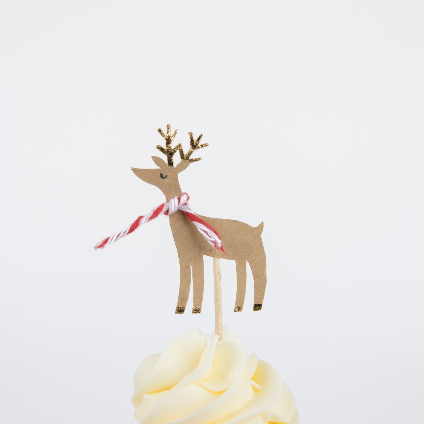 A Reindeer with red and white bakers twine scarves topped on a cupcake.
