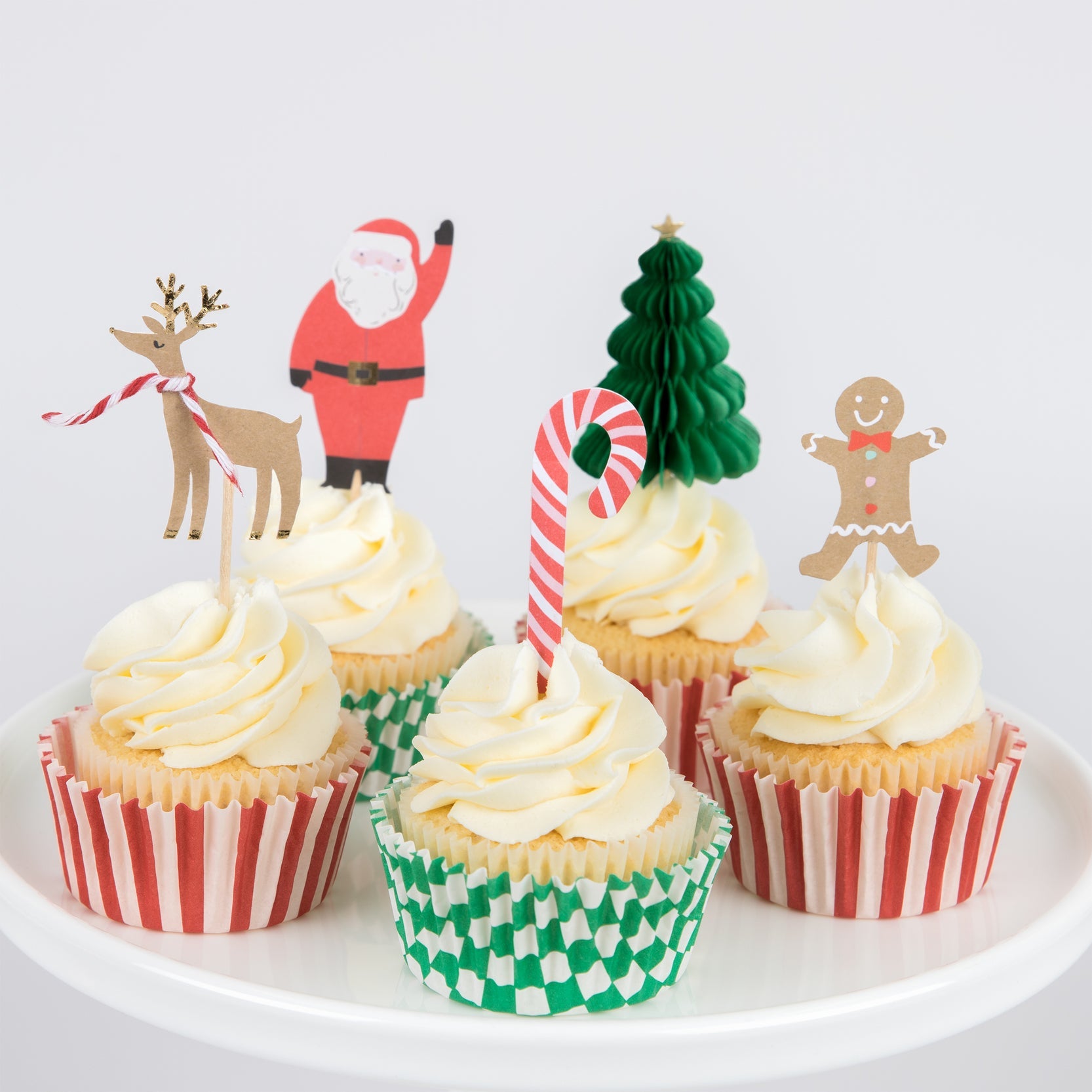 Five cupcakes with various holiday cake toppers.