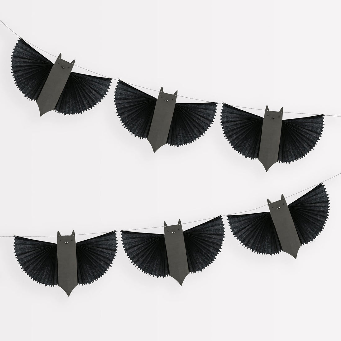 A garland made of paper bats with black tissue paper wings, hanging from a shiny silver metallic cord.