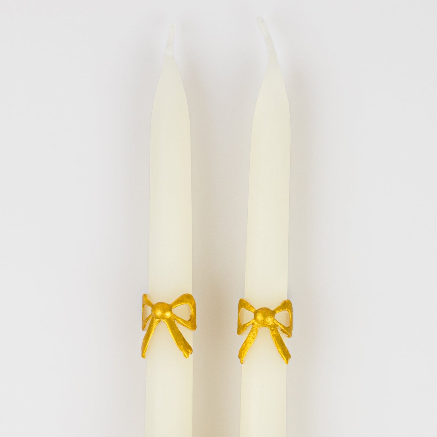 close up of gold bow on taper candles