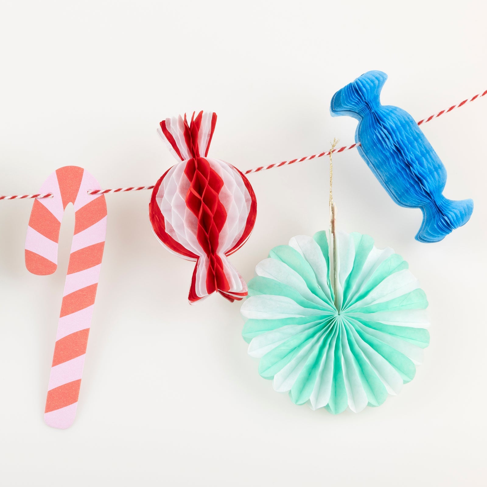 Decorative paper candy and fan decorations on a string against a white background.
