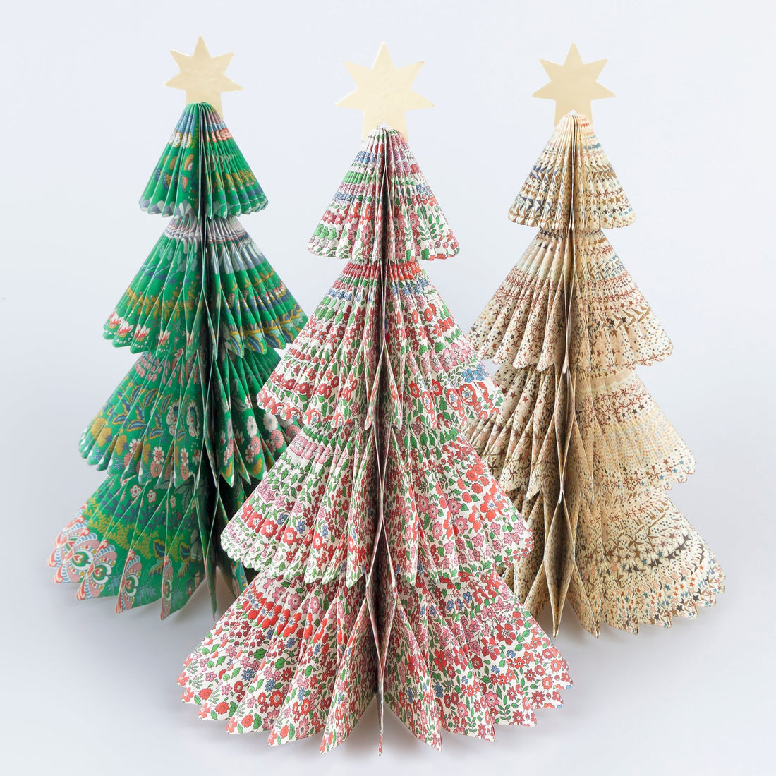 Three paper Christmas trees with floral patterns on a white background.
