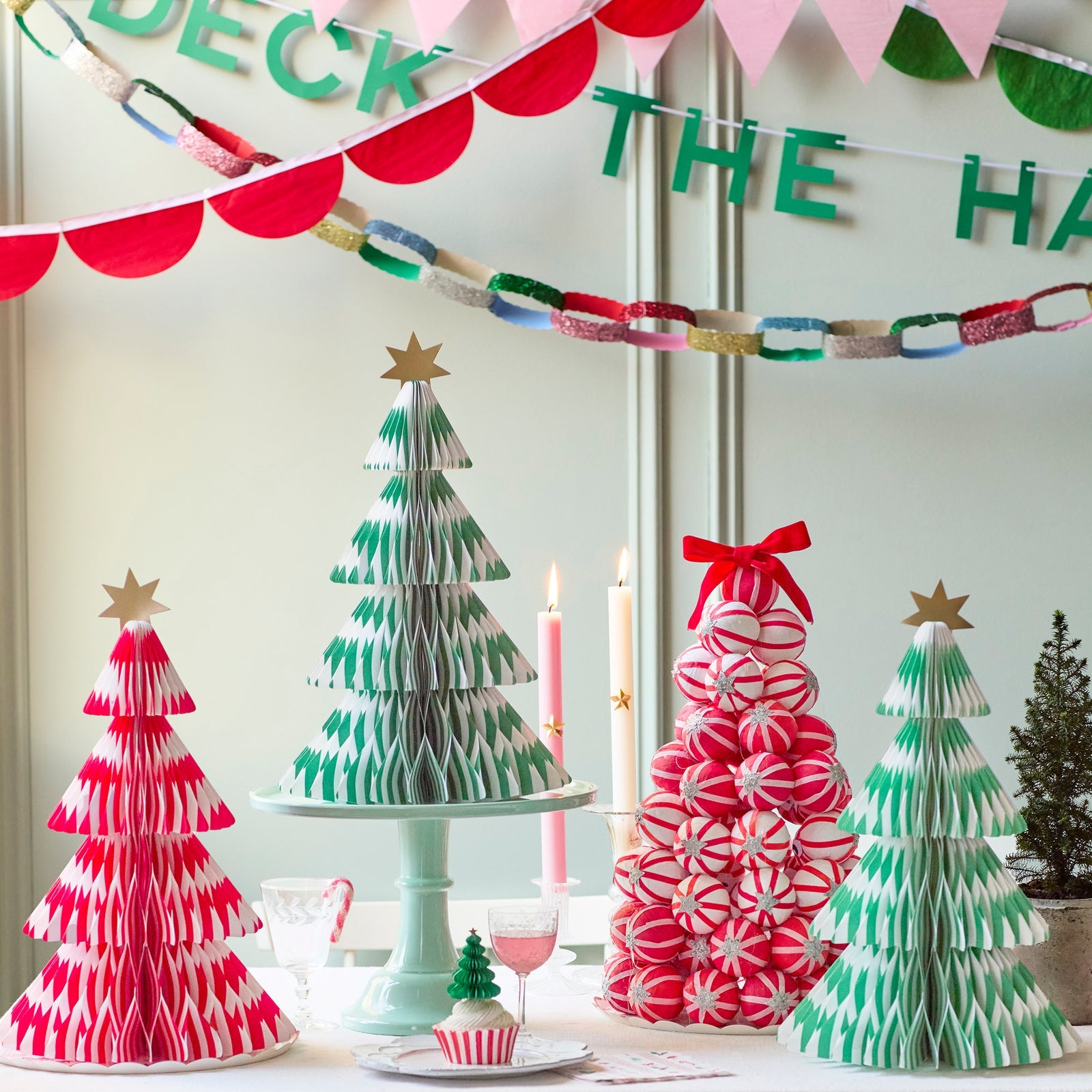 Decorative Christmas trees made from paper with festive decorations on a table.