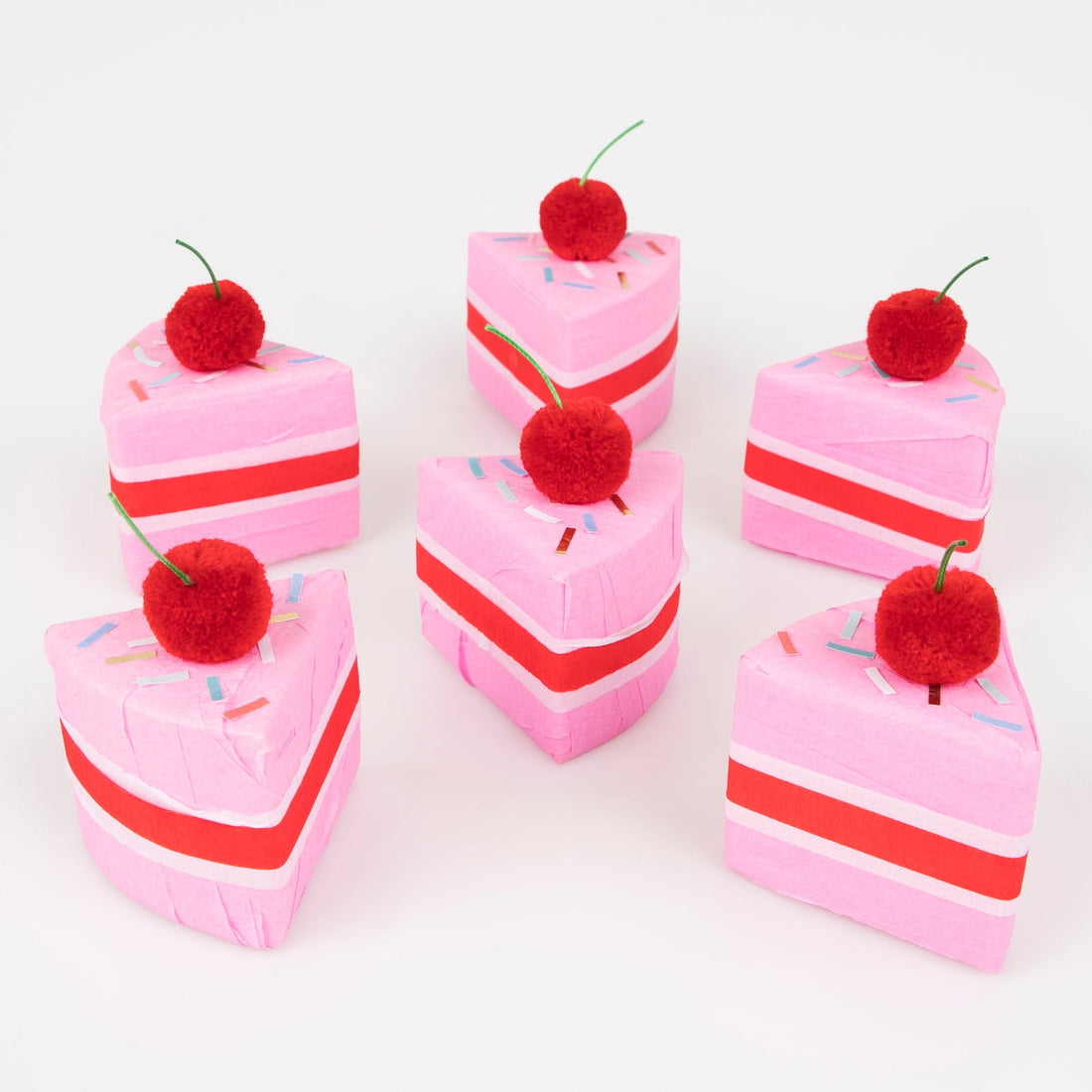 Meri Meri Surprise Cake Slices.  A box of 6 cakes slices crafted with red, white and pink crepe paper.  Each slice is topped with a red pompom cherry with a green cord stalk, and sprinkle stickers.