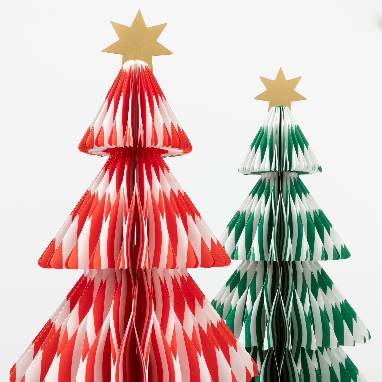 Two paper Christmas trees, one red and white, the other green and white, on a white background.