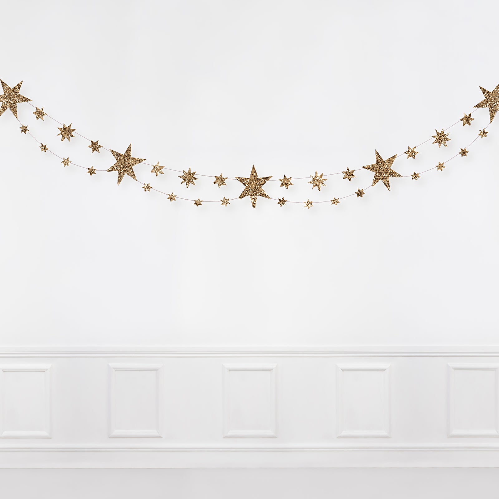 Gold star garland on a white wall.