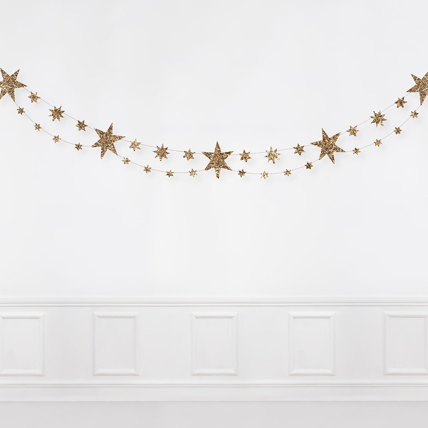 Gold star garland on a white wall.