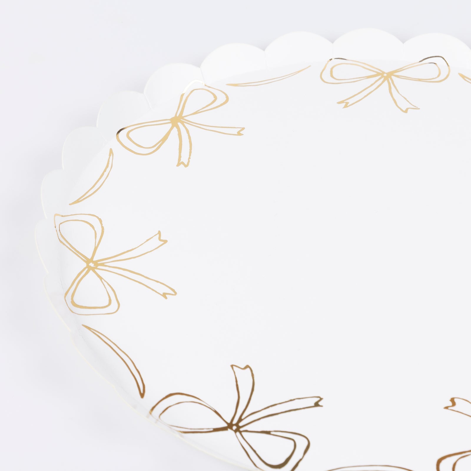 Paper plate by Meri Meri with gold bow illustrations around the edge.