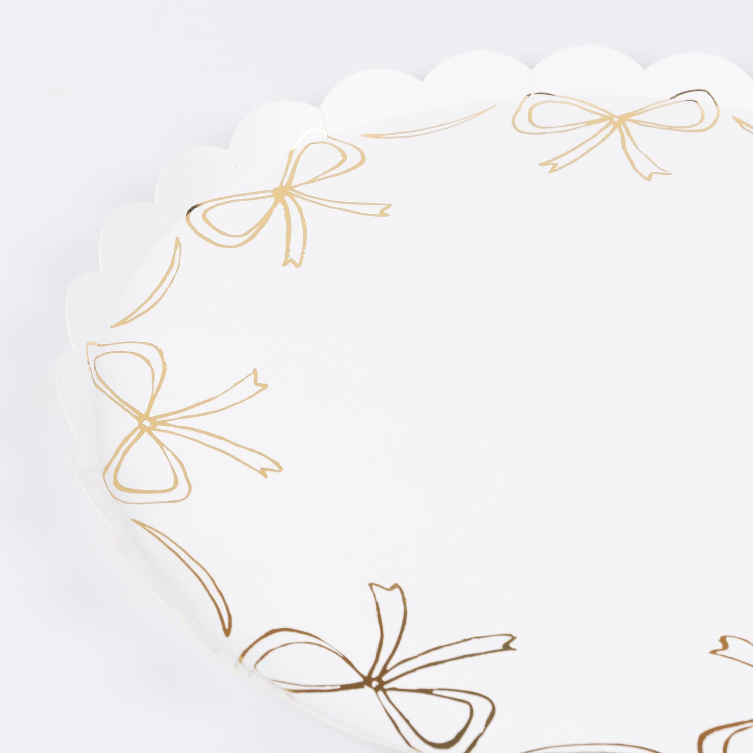 Paper plate by Meri Meri with gold bow illustrations around the edge.