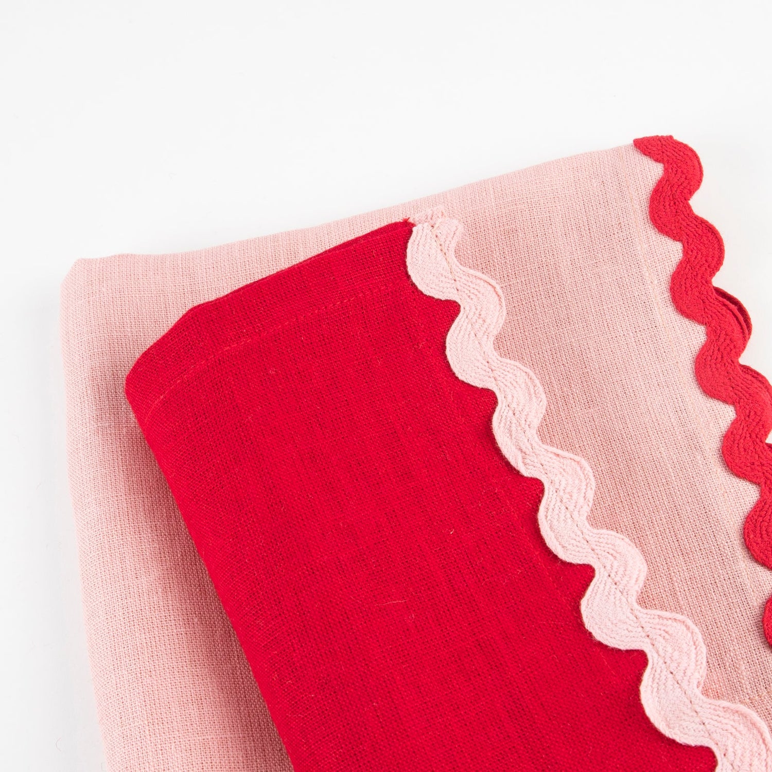 Red and pink napkin with scalloped edge on a white background.