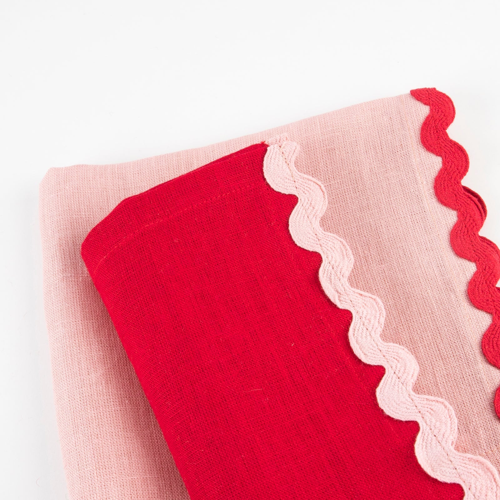 Red and pink napkin with scalloped edge on a white background.