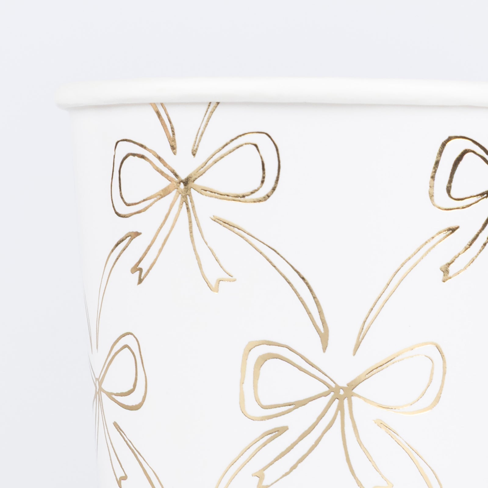 Paper cup by Meri Meri with illustrations of gold bows. 