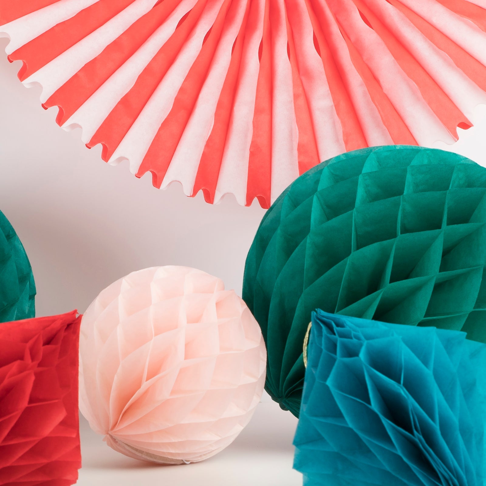 Colorful paper decorations including fans, balls, and honeycomb patterns on a light background.