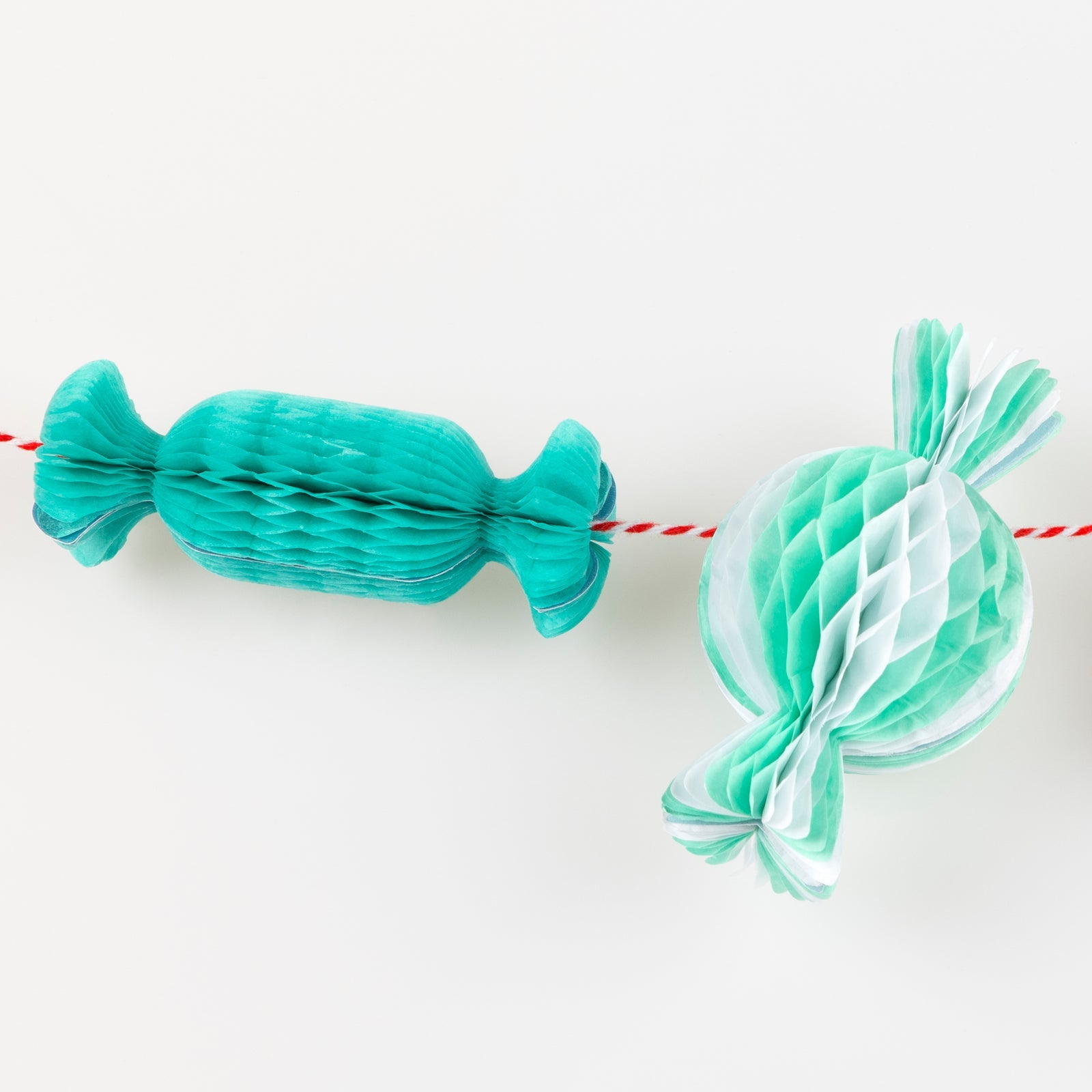Two decorative paper candies, one teal and one white with green stripes, on a white background.