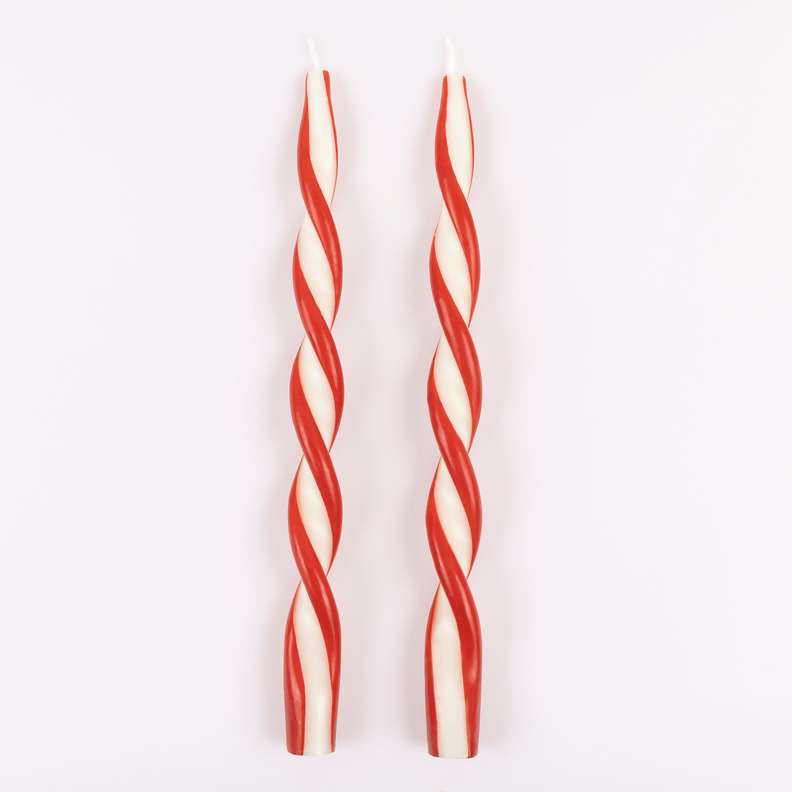 Two red and white striped candles on a light gray background.