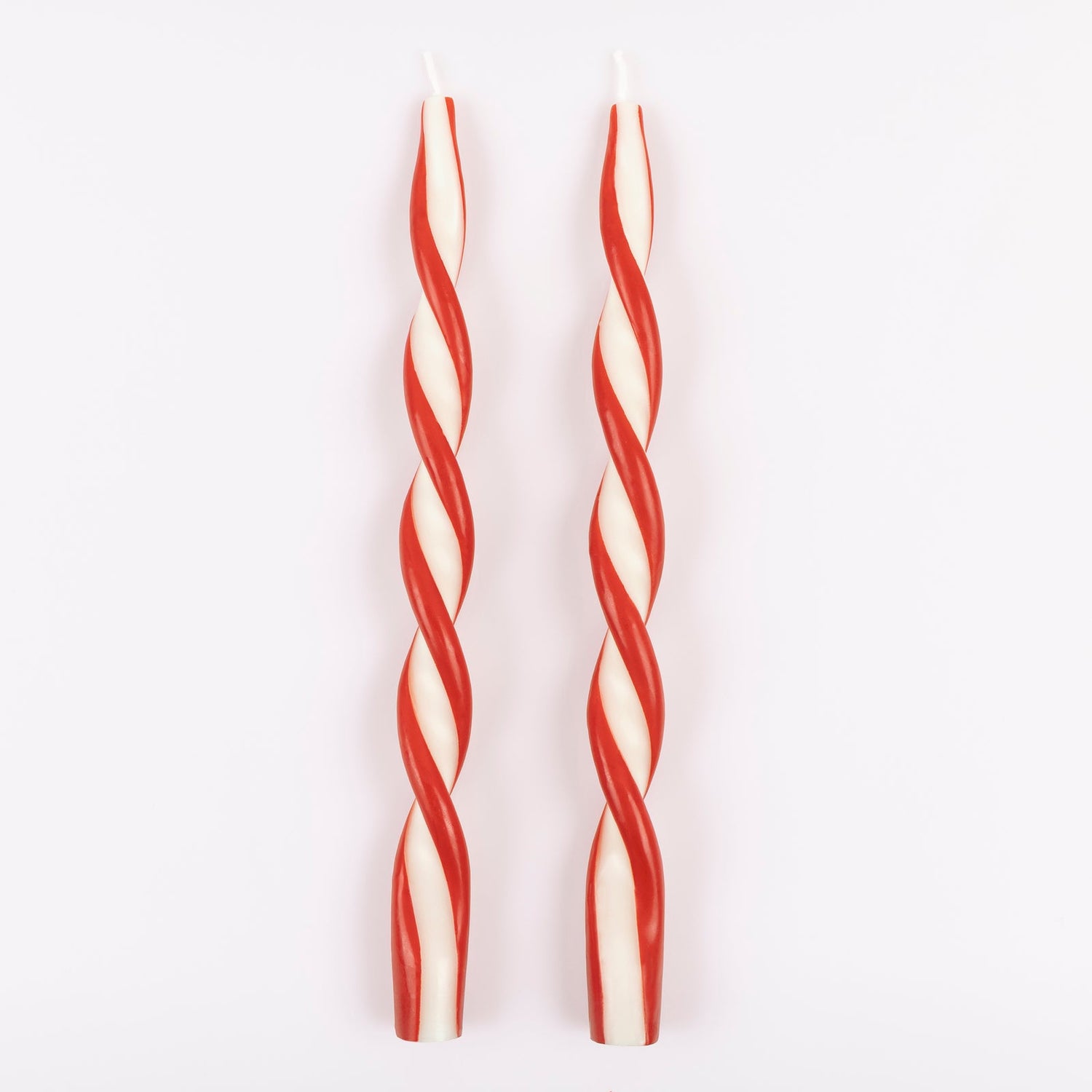 Two red and white striped candles on a light gray background.