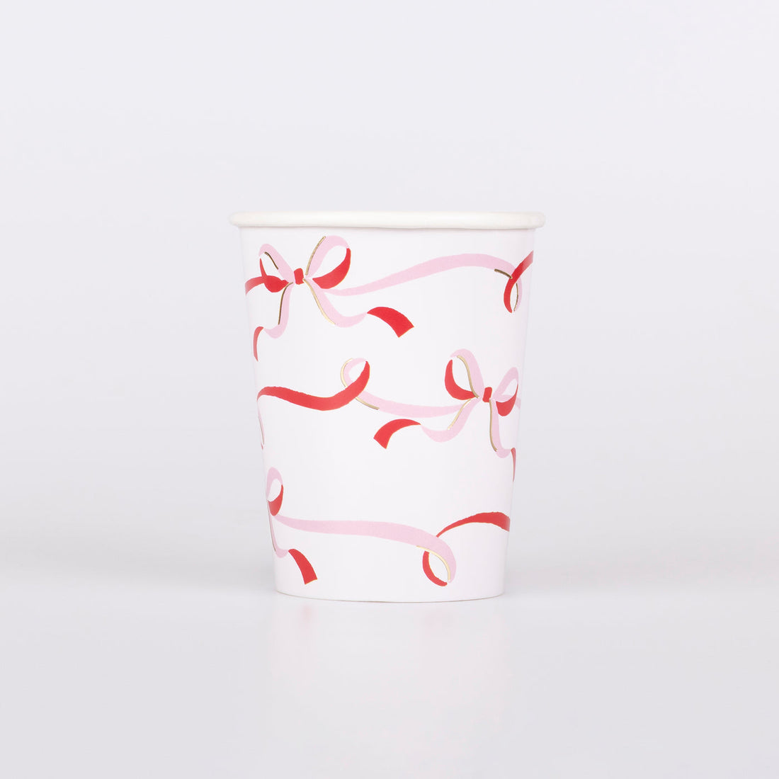 Paper cup with red and pink bow pattern on a white background.