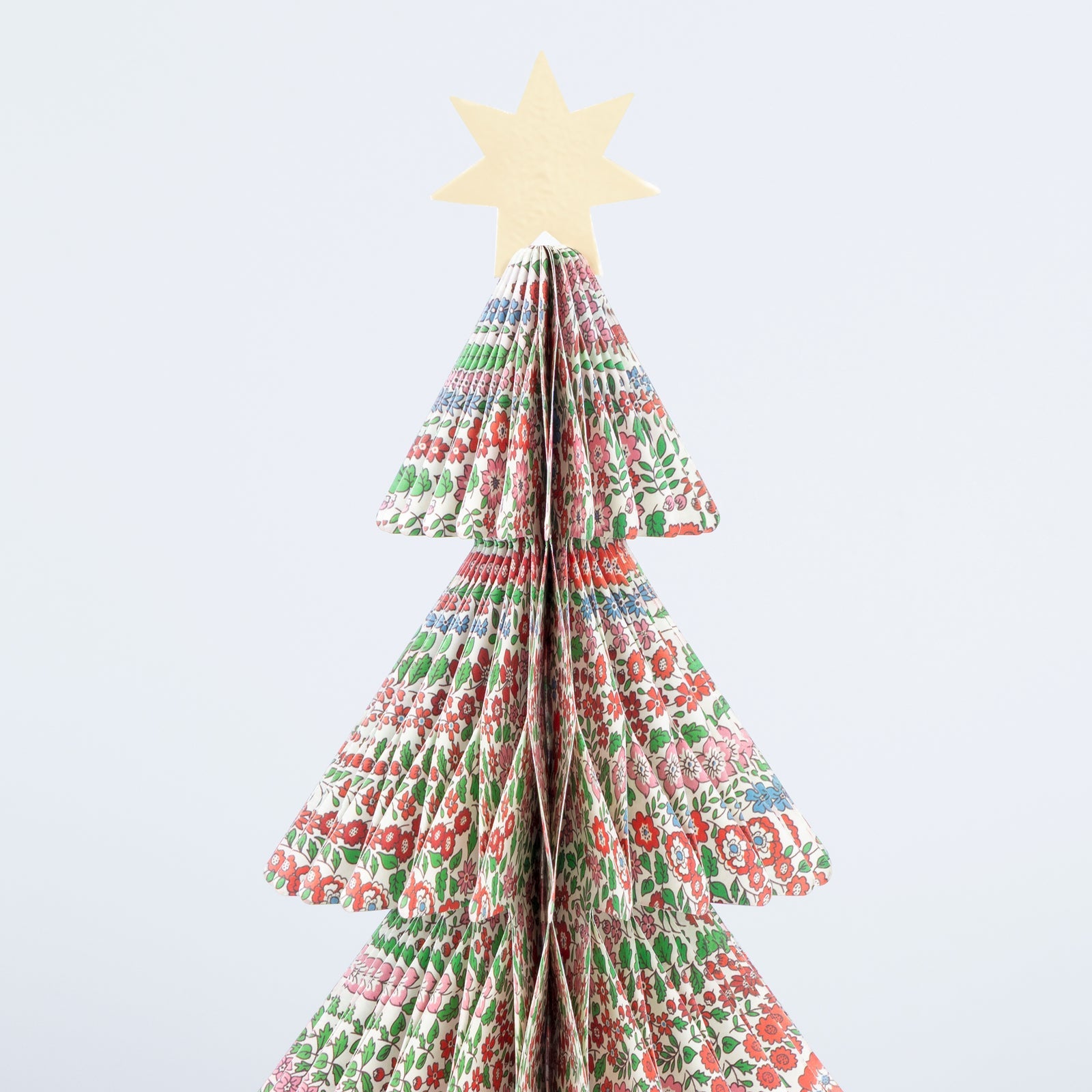Decorative paper Christmas tree with a star on a light blue background.