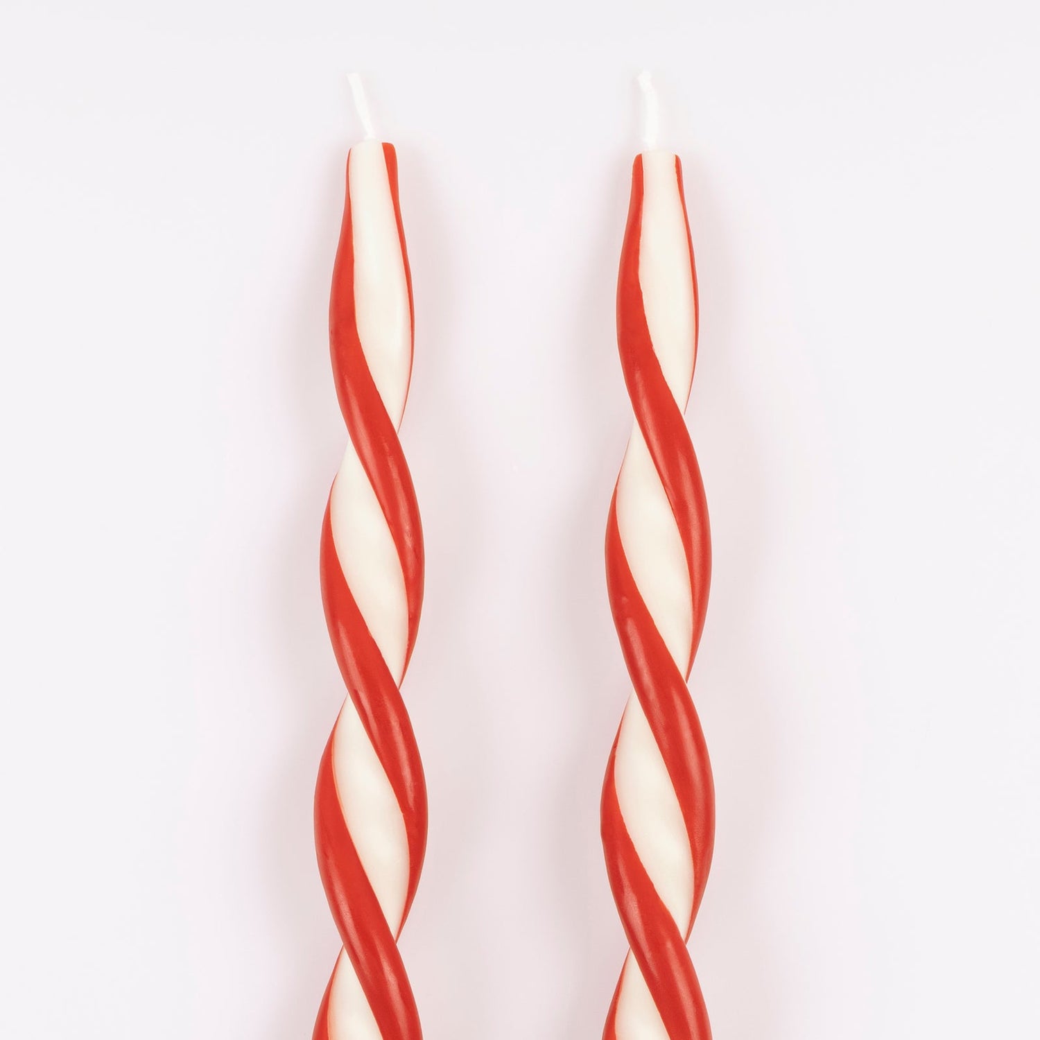 Two red and white striped candles on a white background.