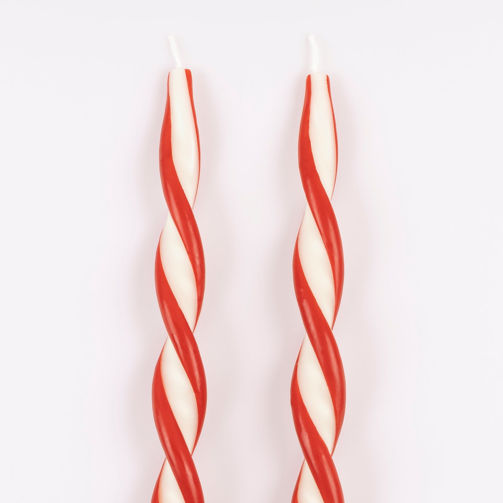 Two red and white striped candles on a white background.