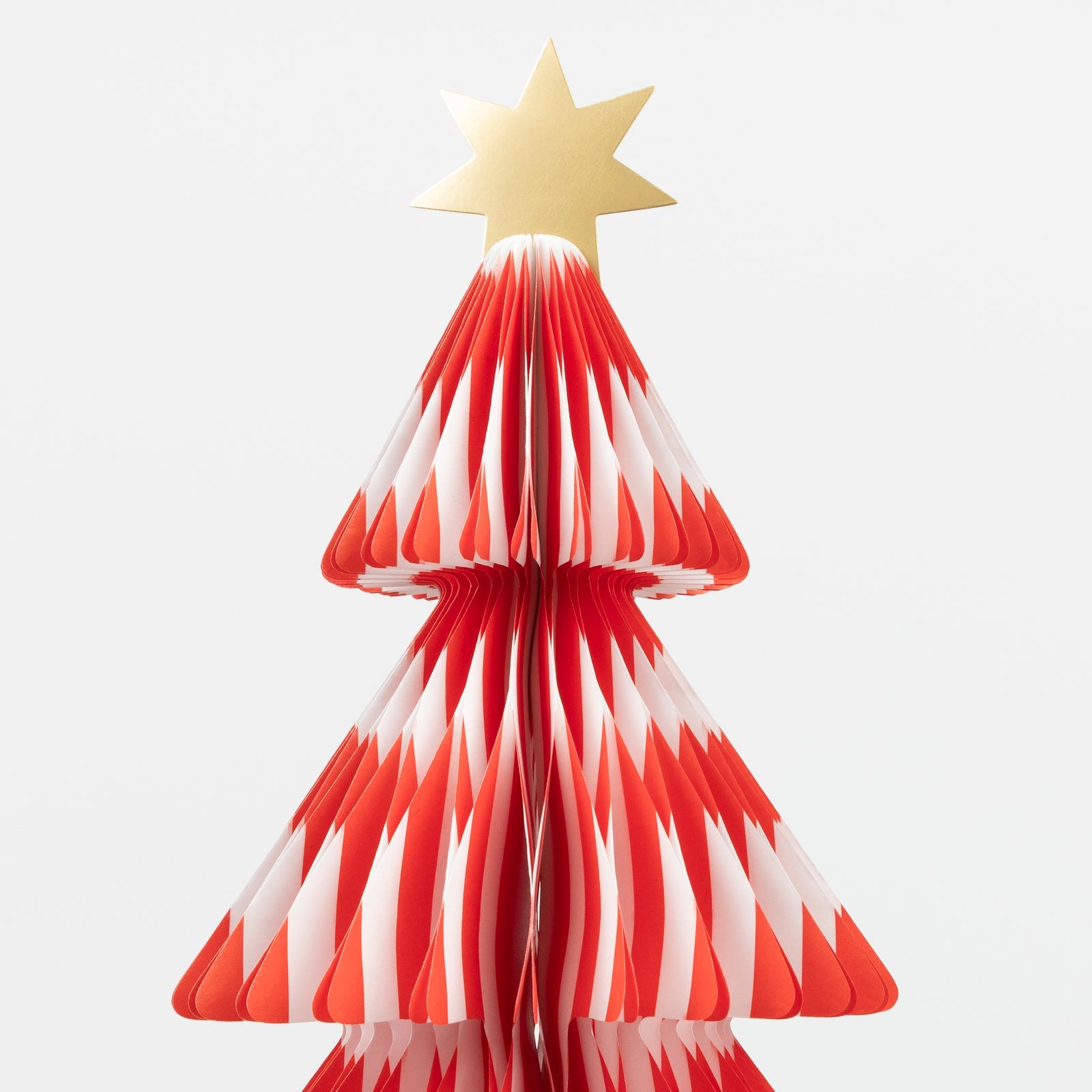 Red and white striped paper Christmas tree with a gold star on a white background.