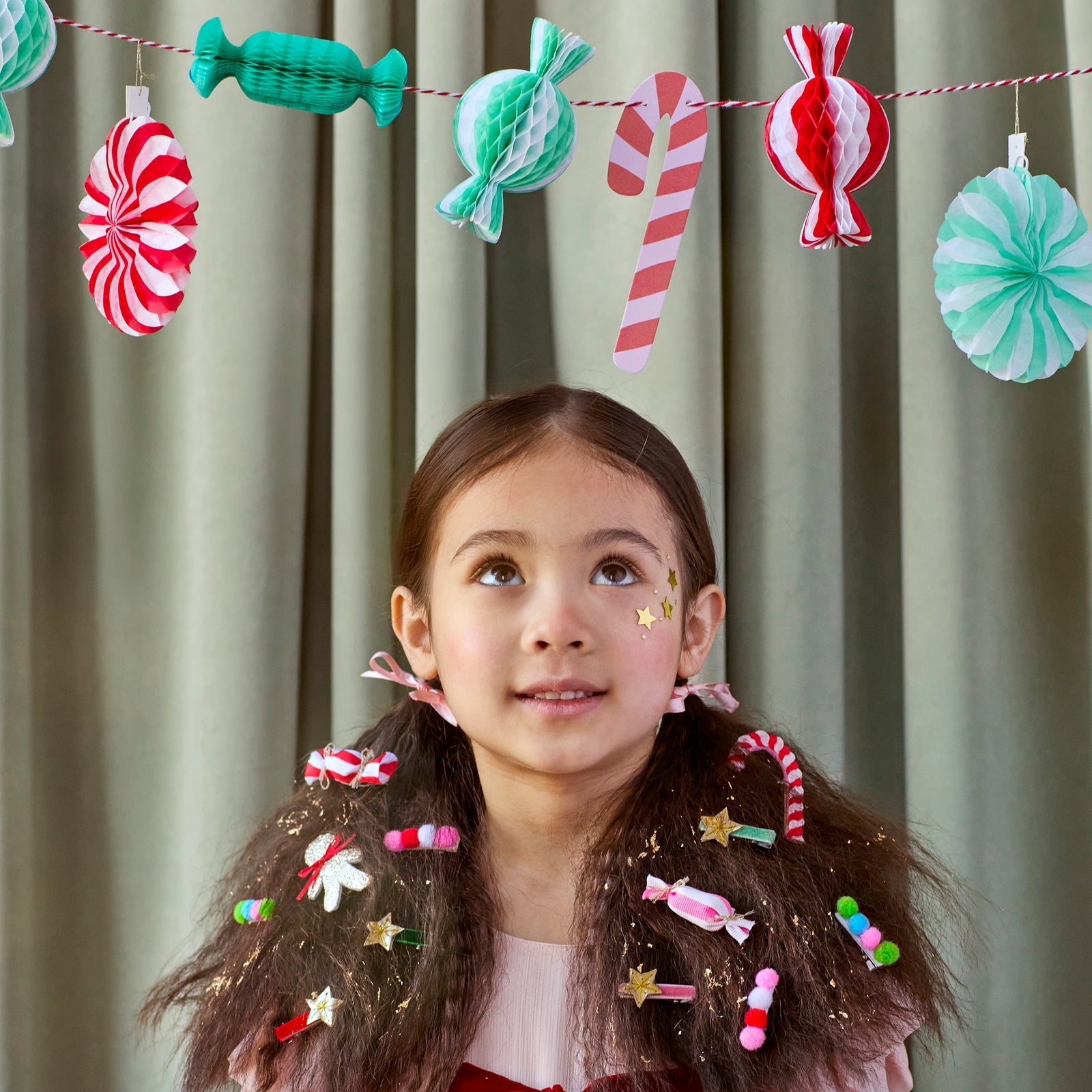Young girl with candy-themed hair accessories and a candy-themed banner in the background.