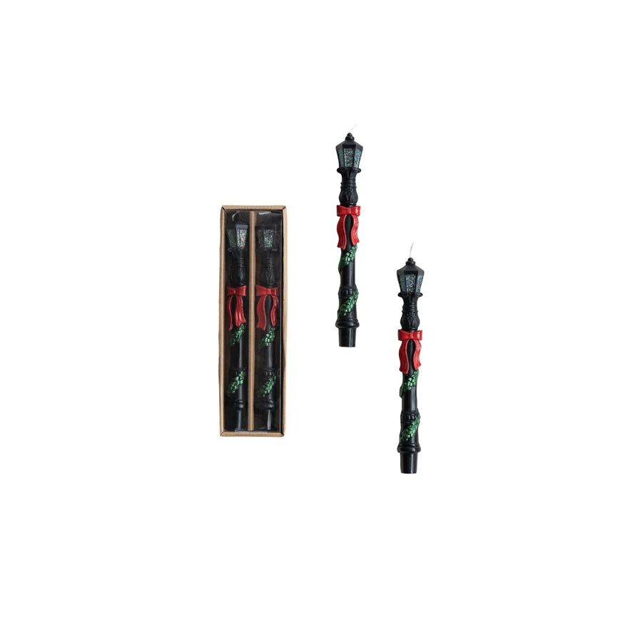 Two black candles with red ribbons and a wooden box on a white background