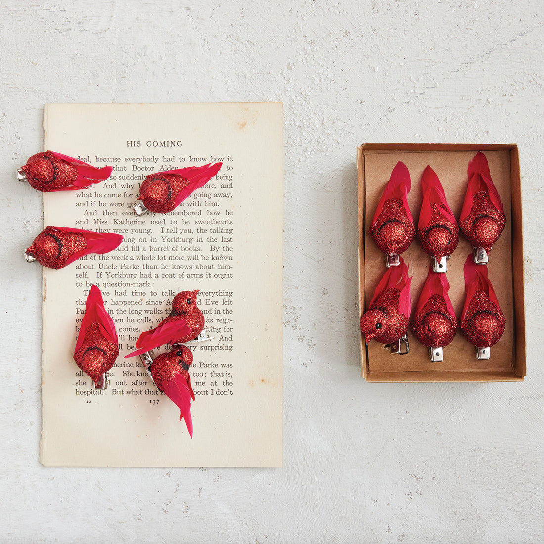 Red decorative items on an open book with a wooden box containing more items.