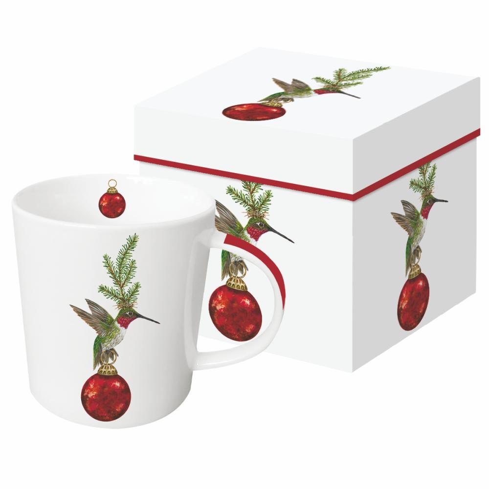 Ceramic mug featuring the artwork of Vicki Sawyer of a hummingbird with greenery on its head standing on a red ball ornament. 