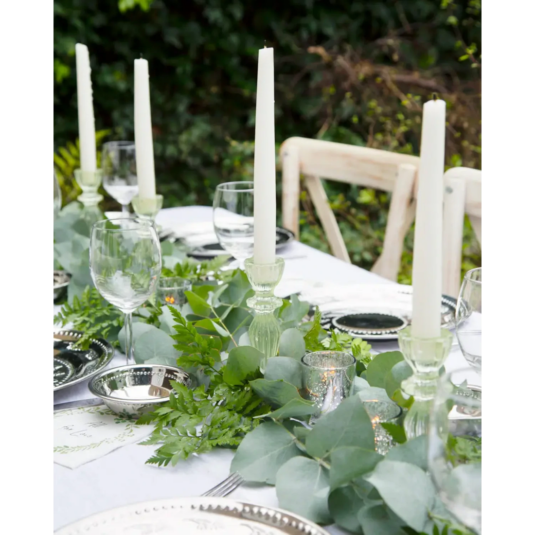 Dinner table set with green pressed glass taper candle holders on it. 