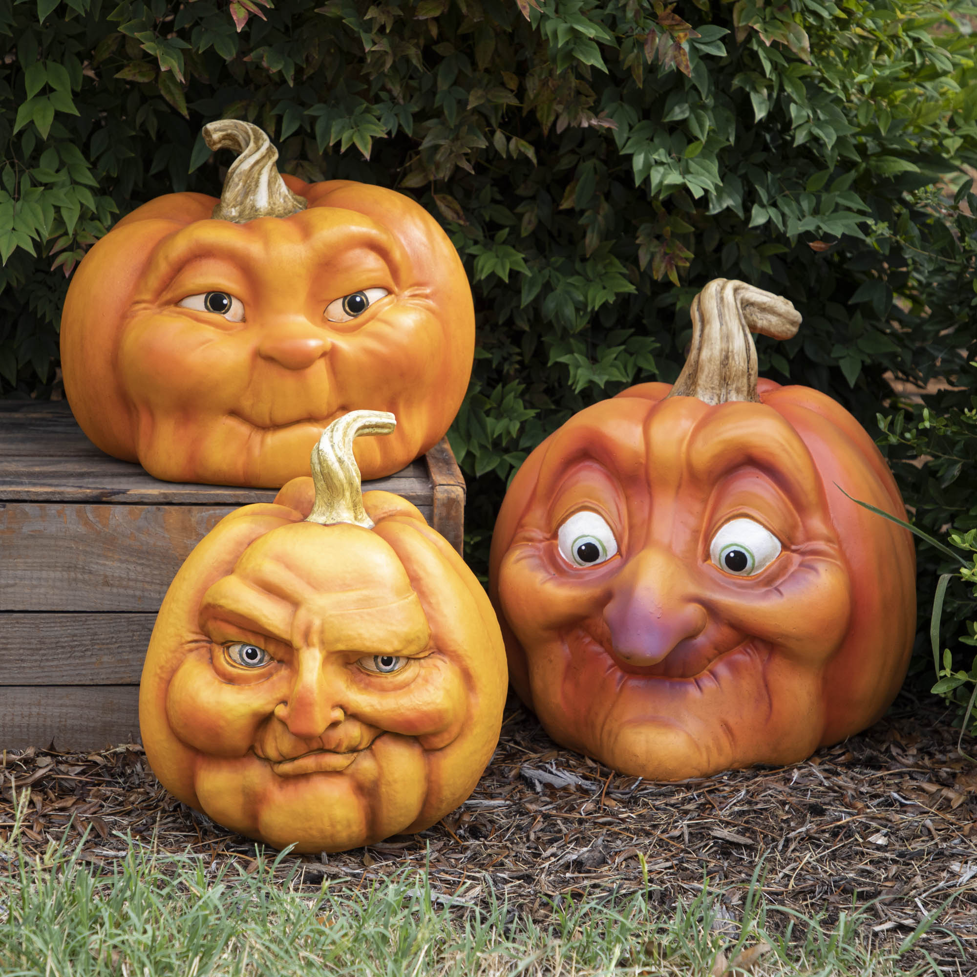 Three resin pumpkins with assorted faces on them.