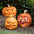 Three resin pumpkins with assorted faces on them.