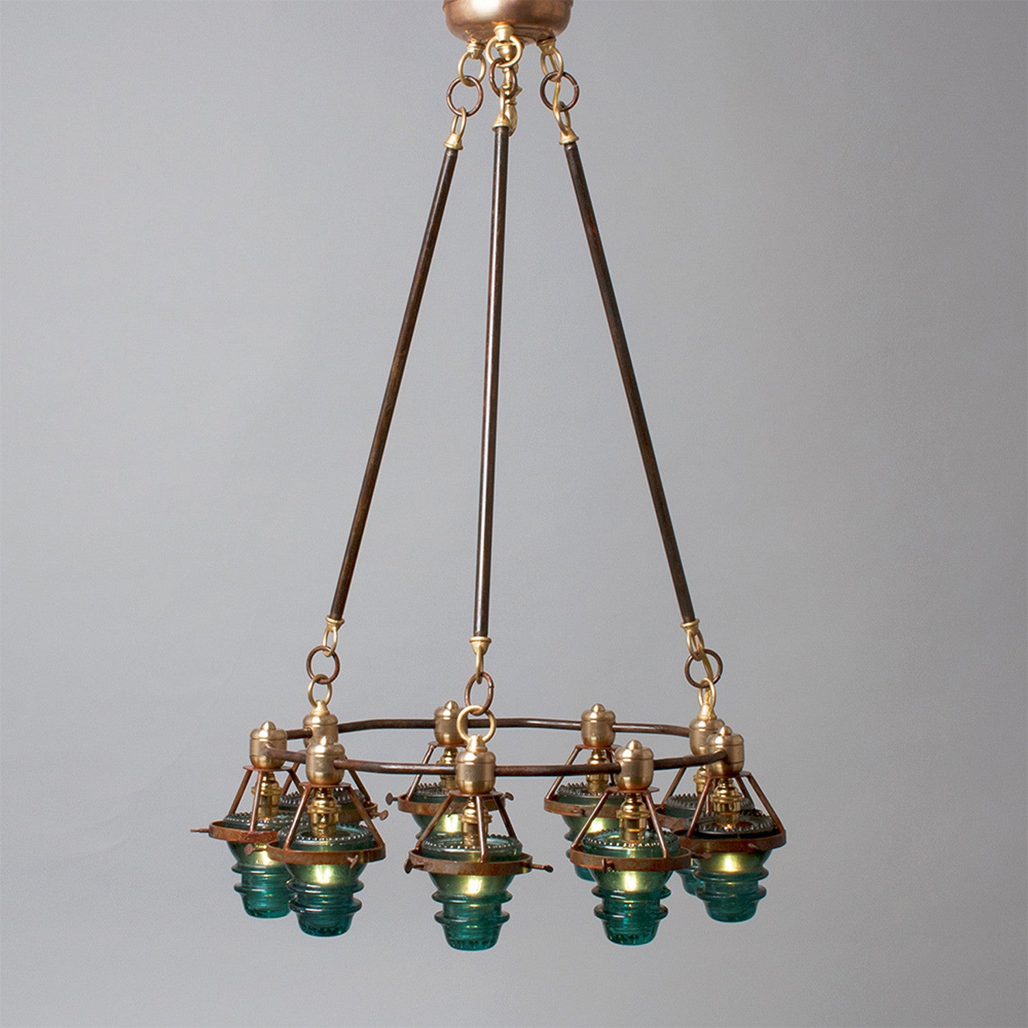 Antique bronze chandelier with multiple glass lampshades and antique insulators suspended from the ceiling, made in the USA by Hester & Cook&
