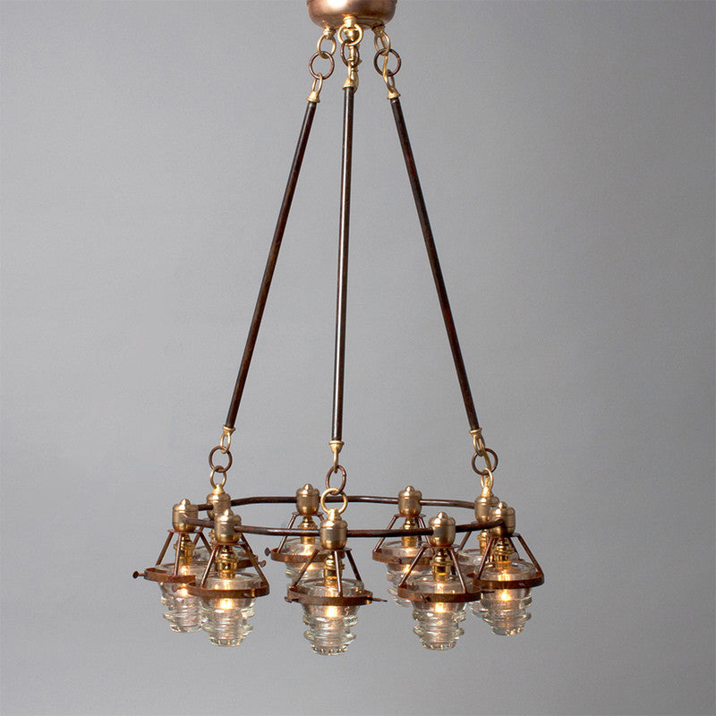 Antique bronze chandelier with multiple glass lampshades and antique insulators suspended from the ceiling, made in the USA by Hester & Cook&