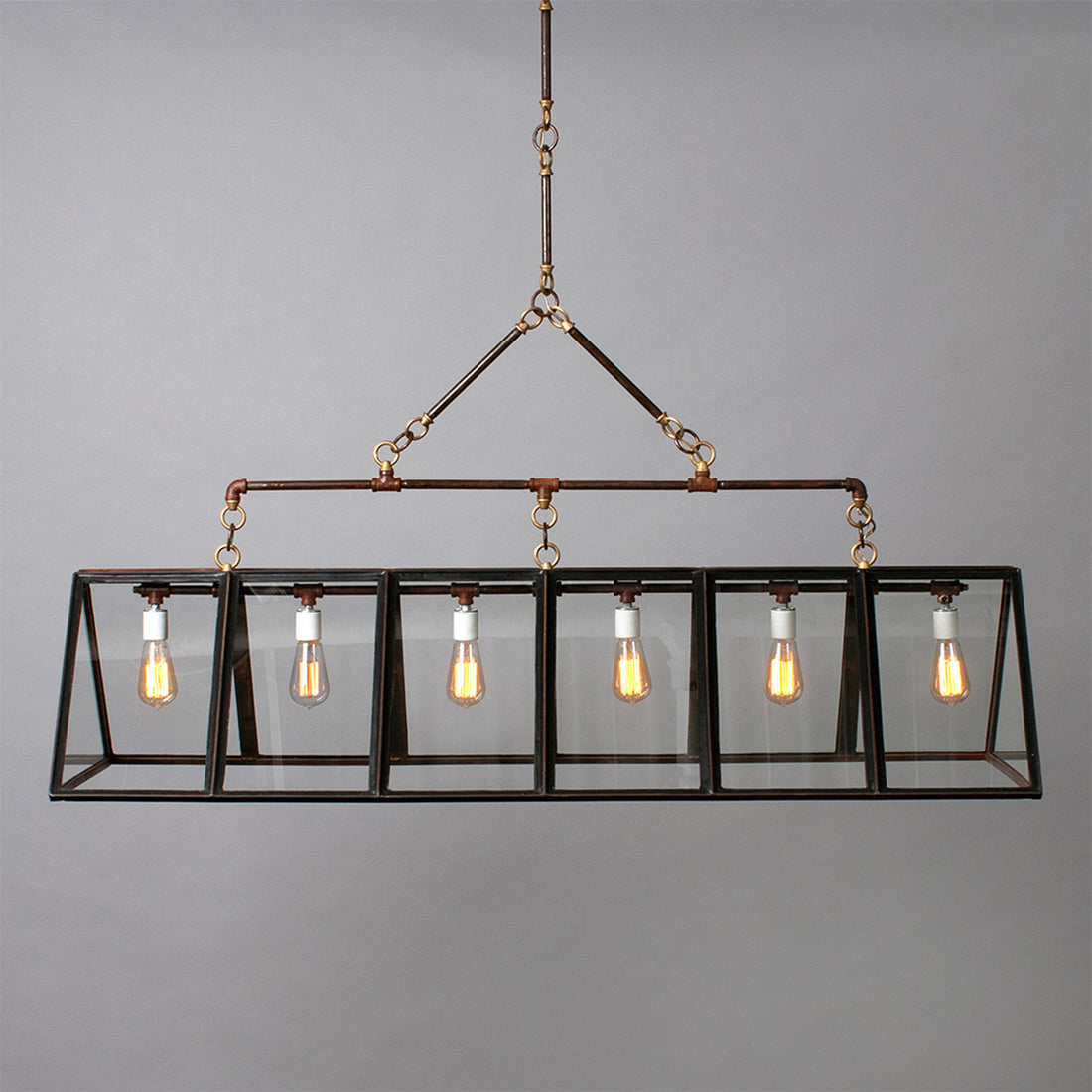 Rectangular metal chandelier with a glazed finish and six exposed light bulbs in a glass and metal box frame, hanging against a plain gray background.