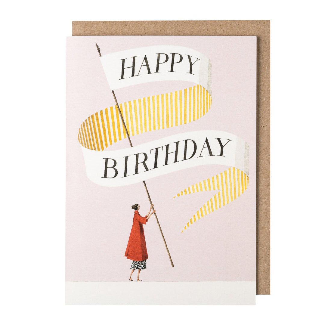 A greeting card featuring a stylized illustration of a woman in red holding a gigantic banner on a pole, which reads "HAPPY BIRTHDAY" on the front and is decorated with gold and white stripes on the back, over a light pink background. The included kraft paper envelope is tucked behind the card.