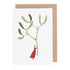 A white greeting card featuring a whimsical illustration of a small woman in a red dress holding up a gigantic sprig of mistletoe by the stem. Kraft paper envelope included.