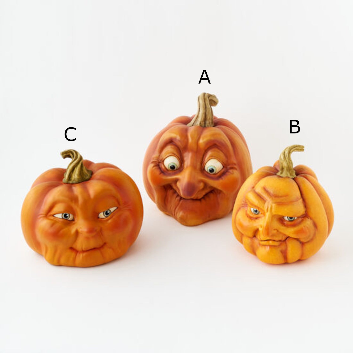Three resin pumpkins with assorted faces on them.