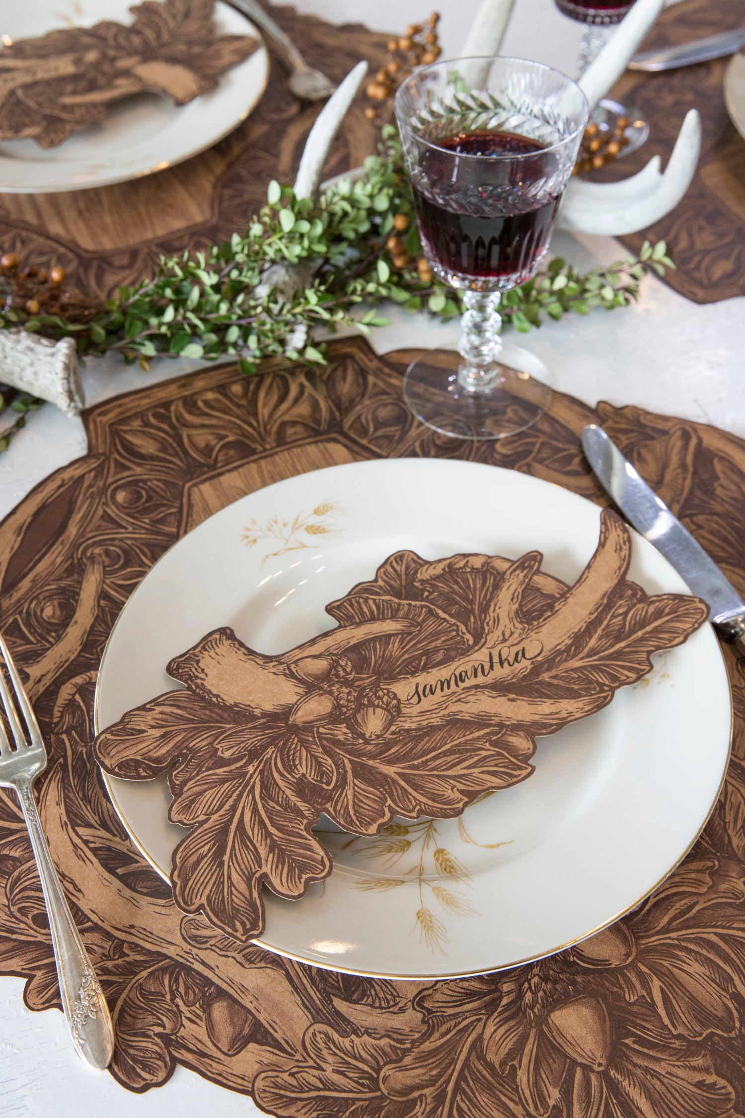 An Antler Table Accent with &quot;Samantha&quot; written on the antler resting on the plate of a rustic place setting.