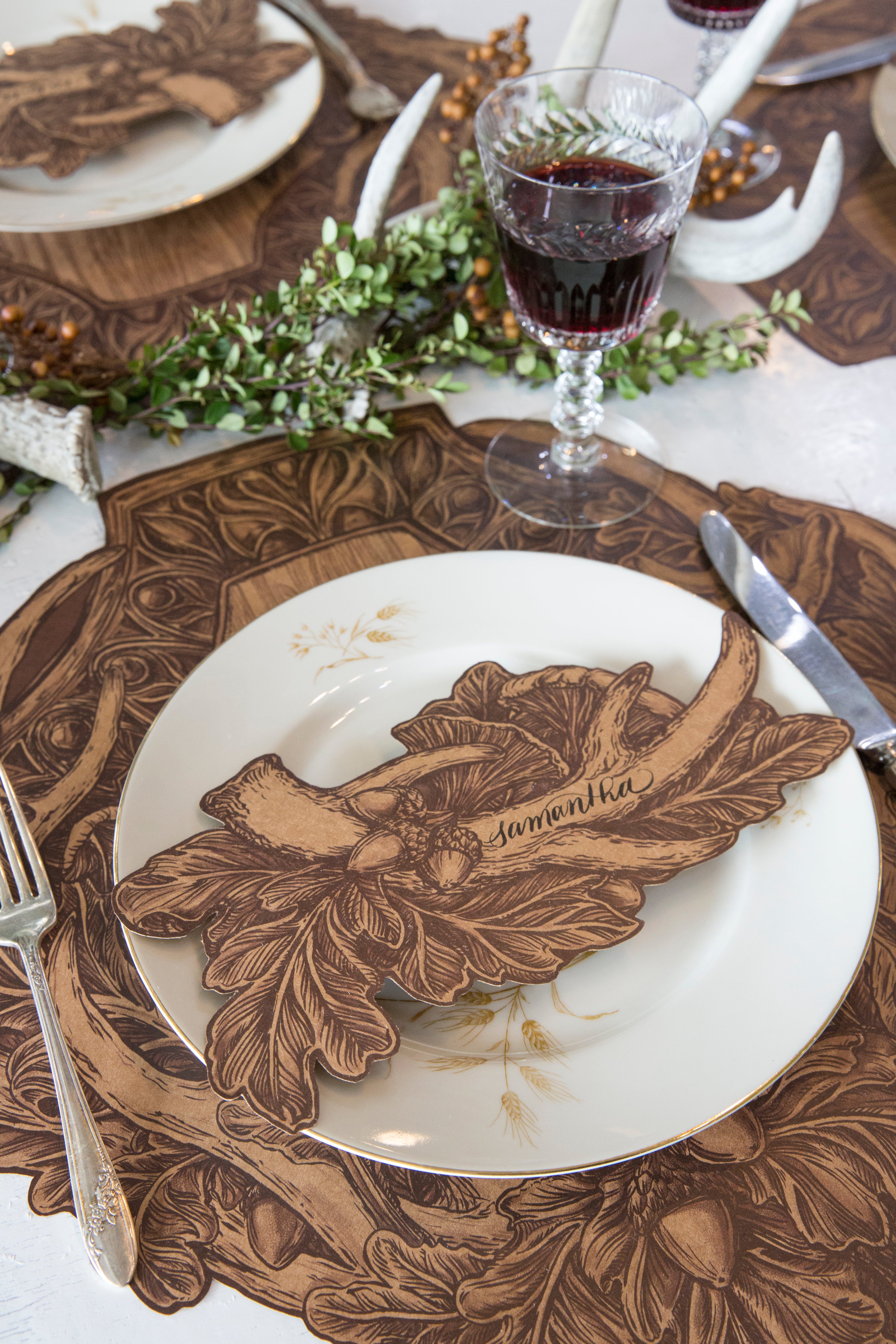 An Antler Table Accent with &quot;Samantha&quot; written on the antler resting on the plate of a rustic place setting.