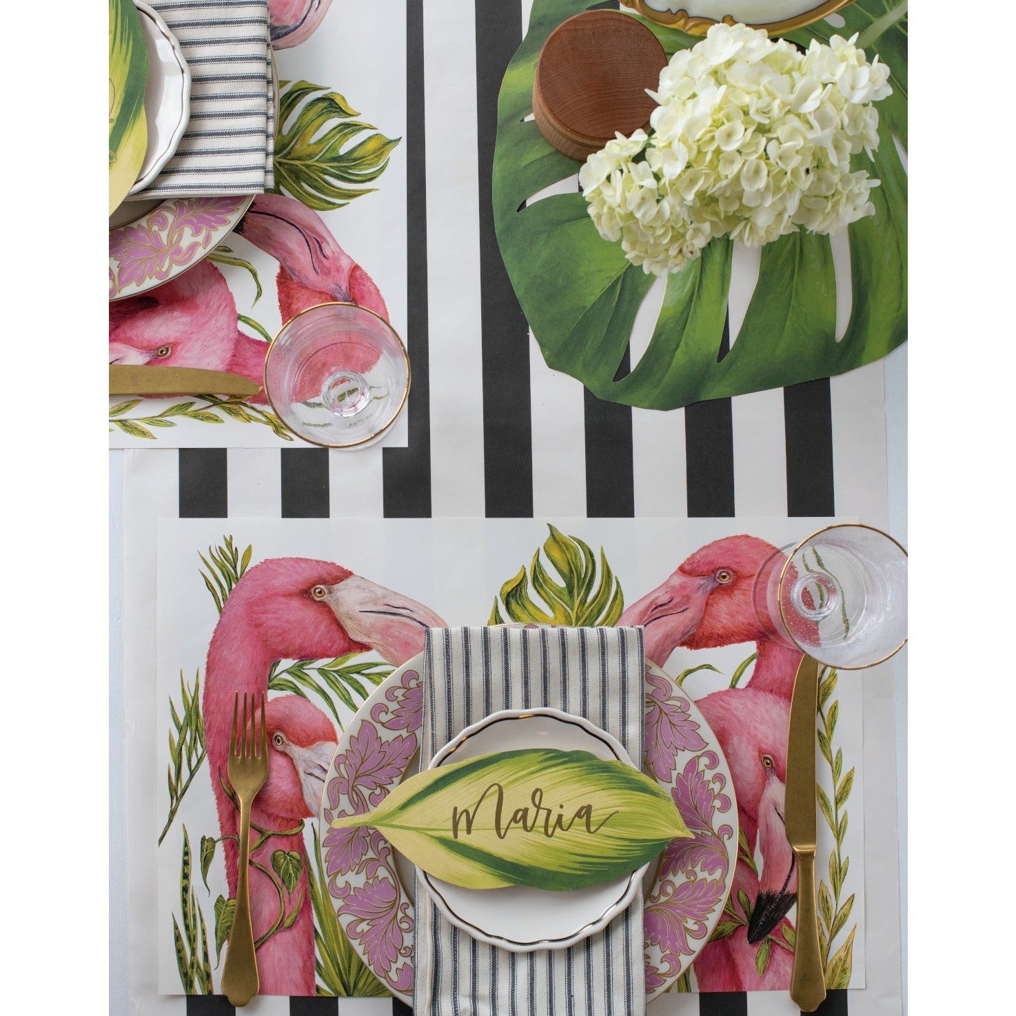 Elegant Hester & Cook Die-cut Monstera Placemat place setting with pink flowers and a black and white striped tablecloth.