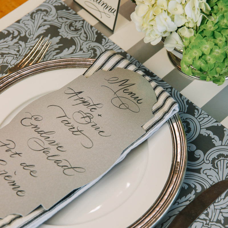 Close-up of Silver Frame Table Accent resting on a plate in an elegant place setting with a menu written in beautiful script.