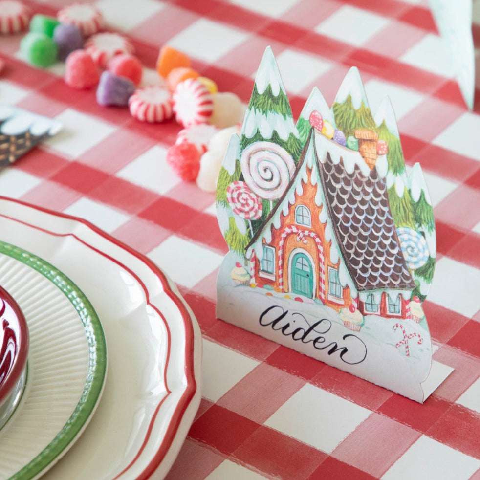 Close-up of a Gingerbread Place Card labeled "Aiden" standing next to the plate of a holiday place setting.