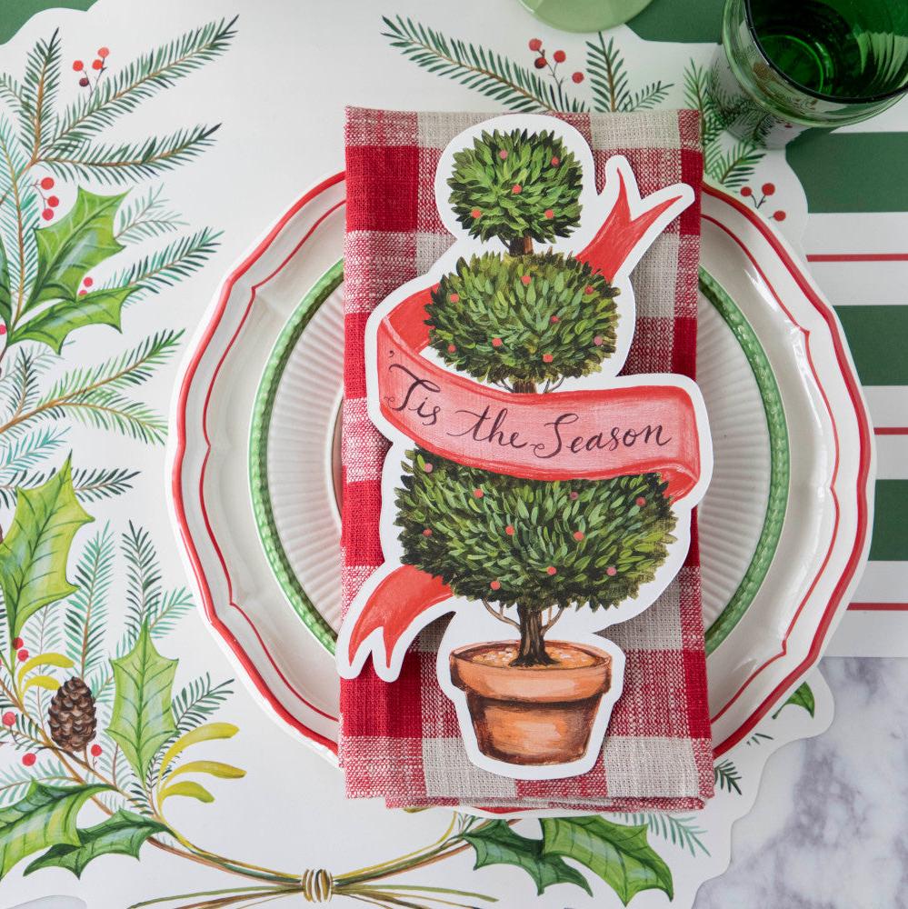 A die-cut illustration of a potted shrub manicured into three balls, with a blank red ribbon twisting around the topiary, creating a space for personalization.