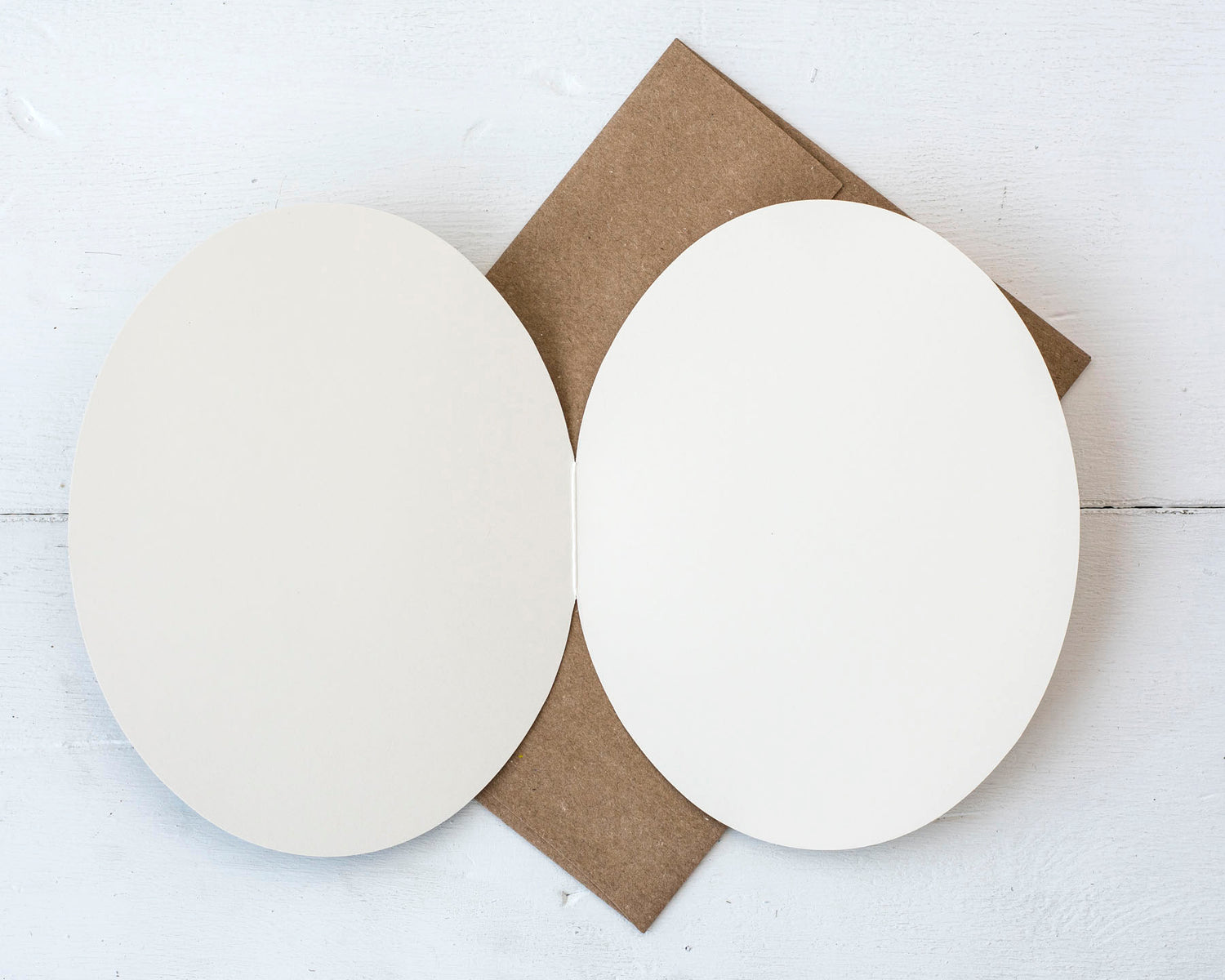 The open card over the kraft envelope, showing the blank white interior of the card.