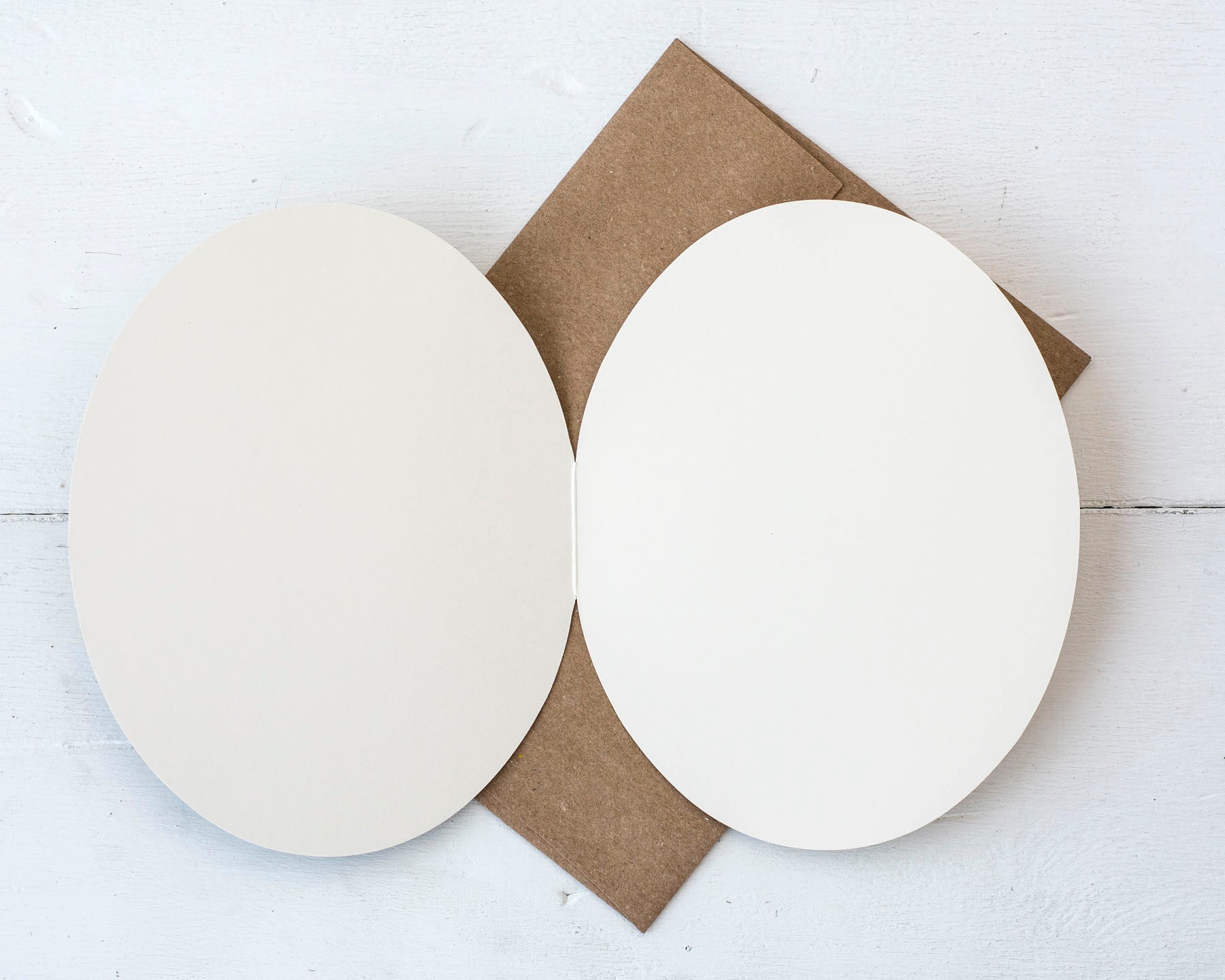 The open card over the kraft envelope, showing the blank white interior of the card.