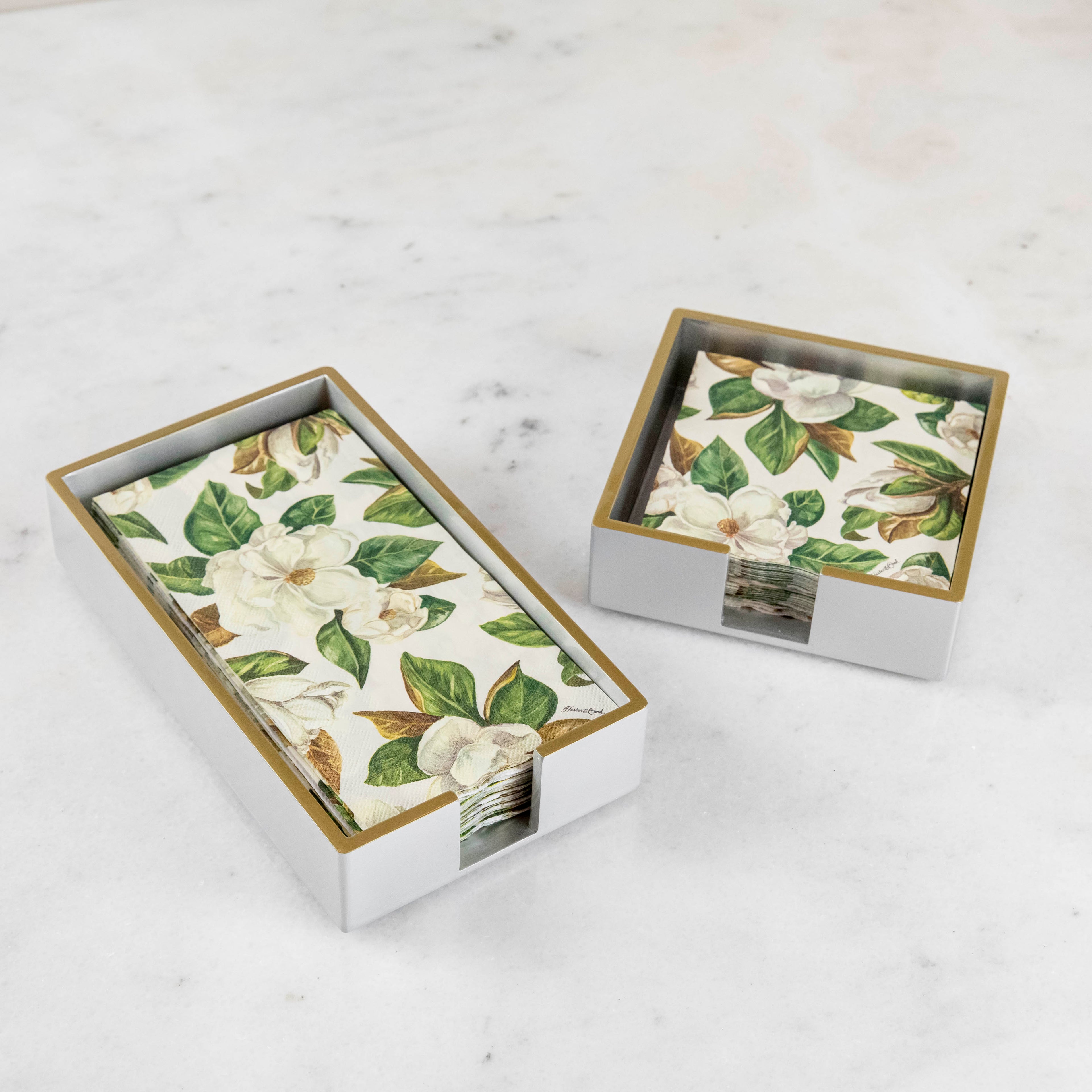 Silver lacquered guest and cocktail napkin holders with napkins inside.