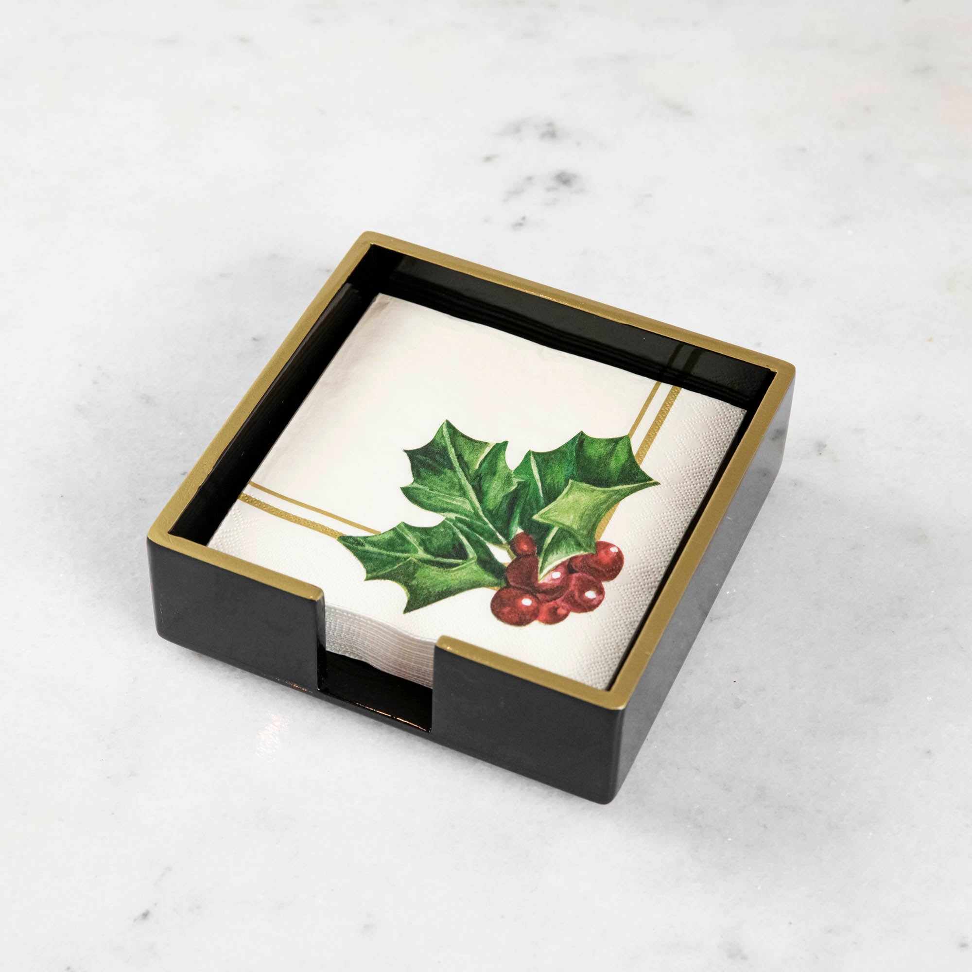 A black lacquered napkin holder with gold trim and a napkin inside of it.