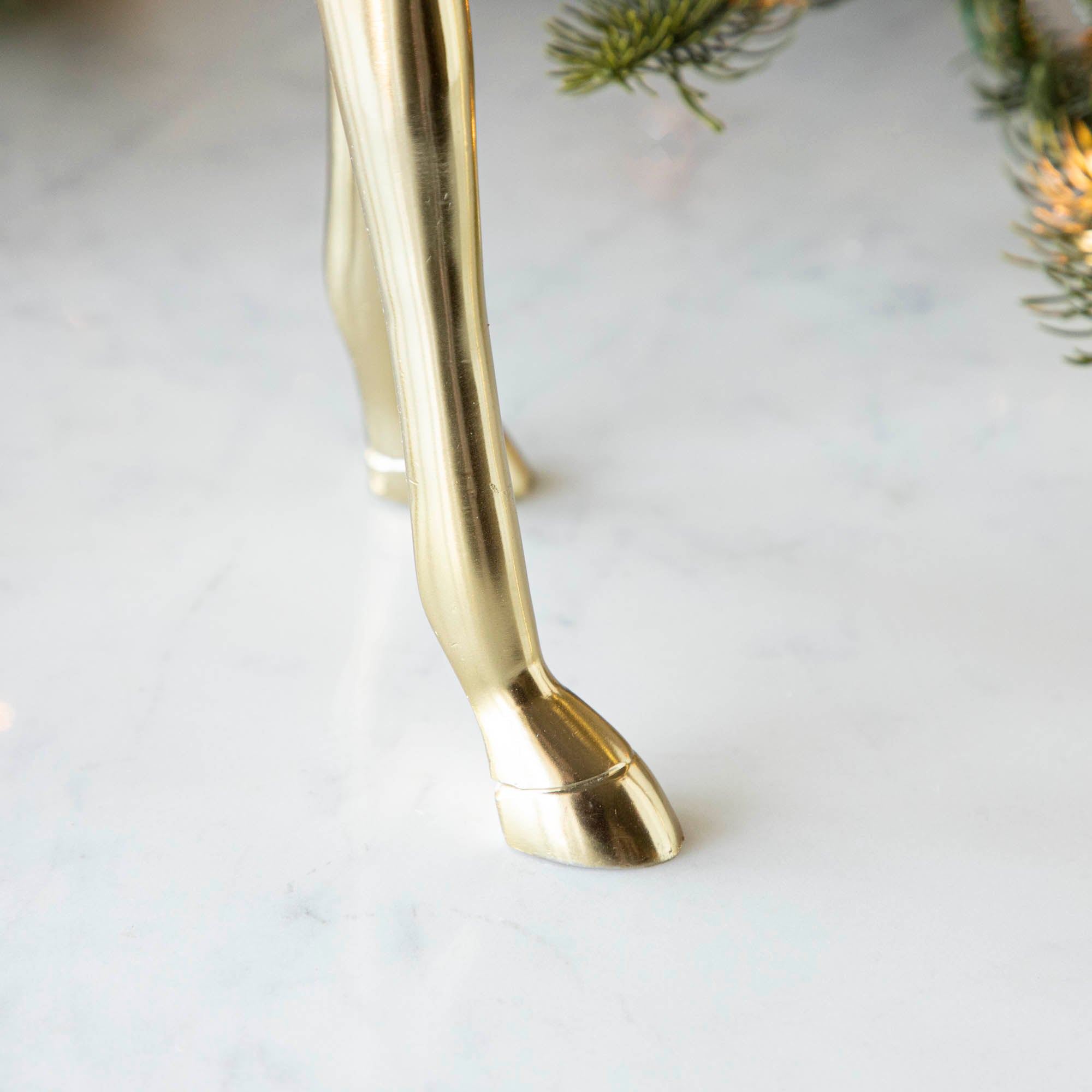 The hoof of a brass deer, on a marble table.