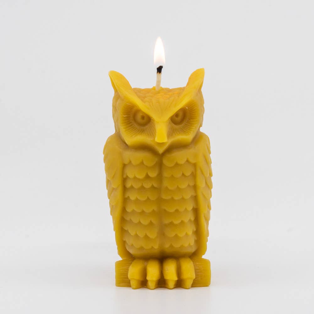 A lit beeswax candle shaped like an owl in natural yellow. 